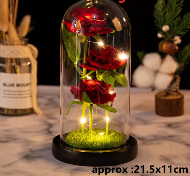 Decorative glass dome with red roses and LED lights on a marble surface.